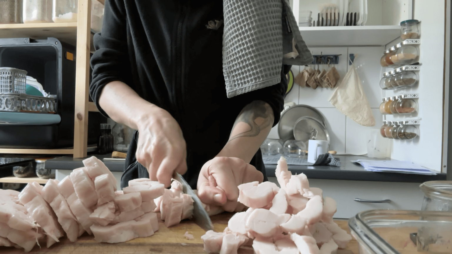 Kate is slicing lard to render. She has a blue towel over her shoulder.